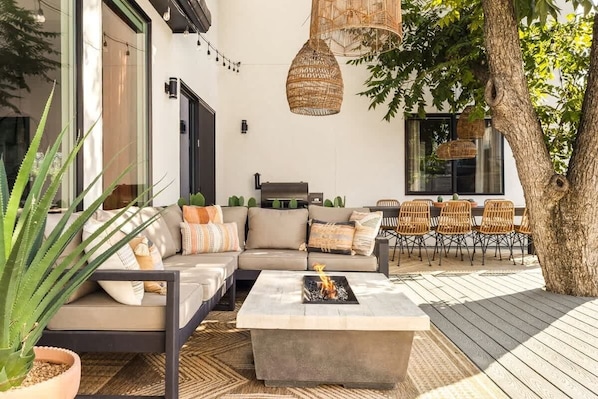 Un espacio al aire libre moderno con sofás, sillas y una chimenea.