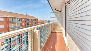Ein Balkon mit Blick auf umliegende Gebäude, einem Metallgeländer und einem gefliesten Boden.
