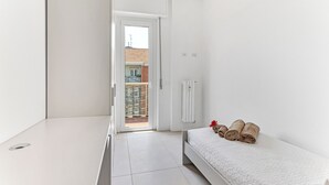Ein schlicht eingerichtetes Schlafzimmer mit Bett, Heizkörper und Blick auf den Balkon.