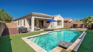 Una propiedad residencial con piscina, terraza techada y césped cuidado.