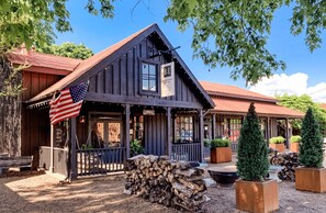 Un bâtiment rustique en bois, doté d’un porche, d’un drapeau américain et d’une enseigne indiquant « OUVERT ».
