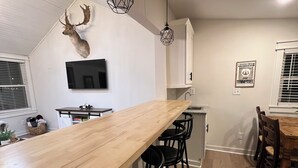Eine moderne Küche mit einer langen Holzauskładung, schwarzen Barhocker und einem aufgehängten Hirschkopf.