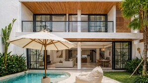 A modern house with a pool, a lounge area with a chair and umbrella, and a dining area. - Villa Janoor by GORO (Keroboken Kelod)