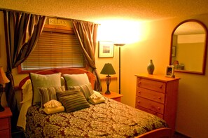 Cozy retreat with a neatly made bed, wooden headboard, and dresser, perfect for a restful stay.