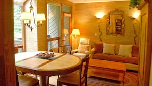 A cozy living room with a dining table, a sofa, and two lamps.
