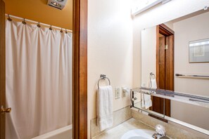 A bathroom with a shower curtain, a sink, a mirror, and a towel rack. - Snowater Condo #85 - Deluxe two Story Condo! (Deming)