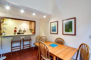 A dining area with a wooden table, four chairs, a blue folder, and two framed pictures on the wall. - Snowater Condo #85 - Deluxe two Story Condo! (Deming)