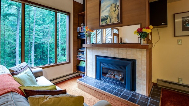 A living room with a fireplace, large windows, and a bookshelf. - Snowater Condo #85 - Deluxe two Story Condo! (Deming)