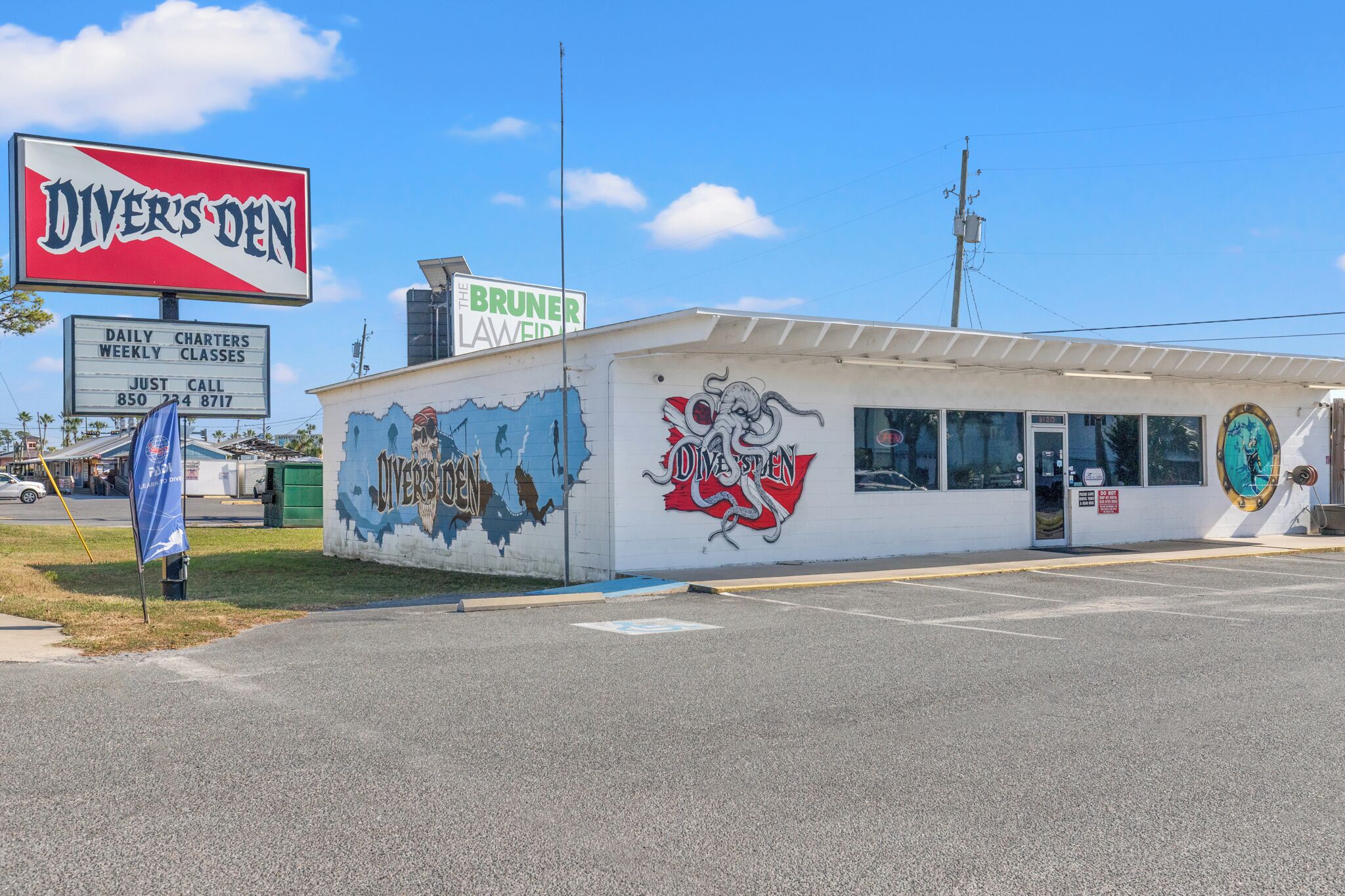 A building with a mural of a sea creature and a sign for 'Diver's Den' offering daily and weekly classes.