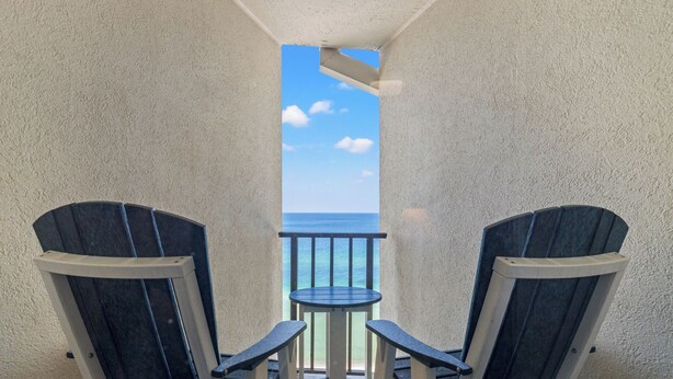 Un balcon avec deux fauteuils Adirondack et une petite table, donnant sur l’océan.