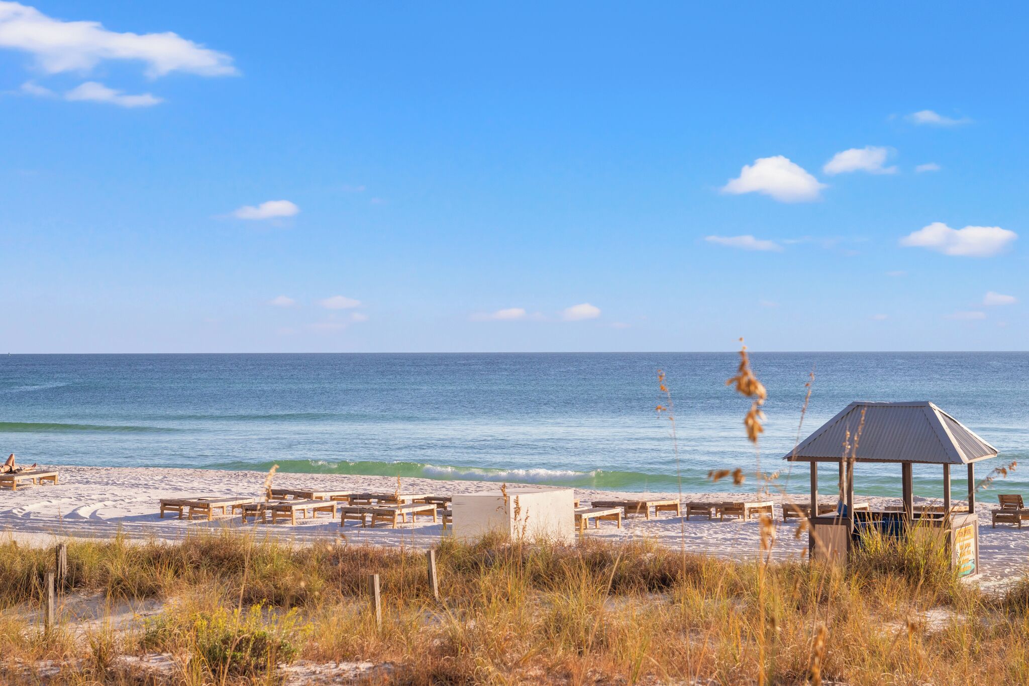 A beach with wooden benches and a gazebo.
