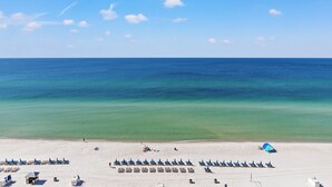 Une plage bordée de rangées de transats et quelques tentes.