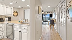 A modern kitchen with white cabinetry, a built-in dishwasher, and a countertop with various appliances.