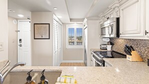 A kitchen with white cabinets, a granite countertop, a microwave, and a toaster.