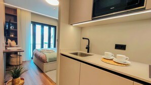 A compact kitchen with a microwave, a sink, and a breakfast setup. - King Studio 2 (Leiria)