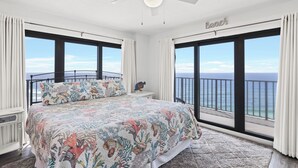 A bedroom with a large bed, a ceiling fan, and a view of the ocean. - 1201 Fall Beachfront Escape—3BR/3BA, Wraparound Balcony, Beach Service (Panama City Beach)
