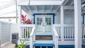 A white building with a blue door and steps leading to a porch.
