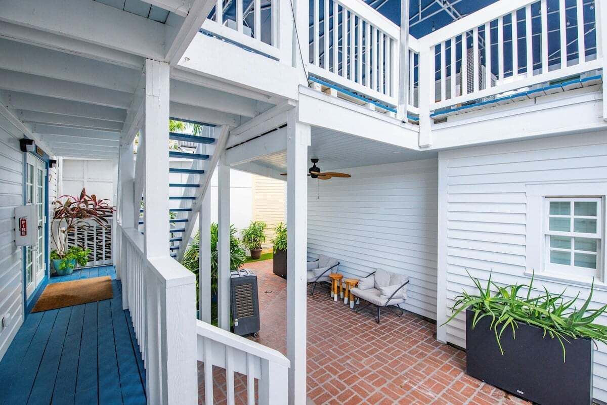 Et overdækket udendørs område med terrasse, møbler og plantekasser.