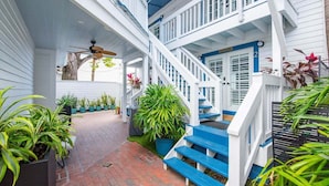 A multi-level wooden house with blue and white exterior, a brick pathway, and potted plants.