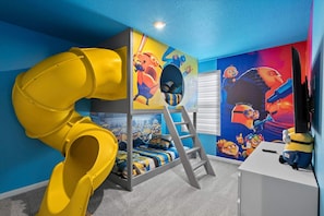 A bunk bed with a slide, a ladder, and a wall mural of animated characters.