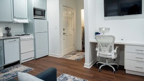 A modern kitchen with white appliances, a dining area with a blue and white rug, and a white office chair. - Cozy studio in Columbia with WiFi, AC (Columbia)