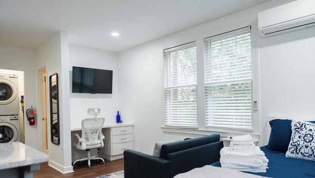 A modern hotel room with a bed, a desk, a chair, a washing machine, and a TV. - Cozy studio in Columbia with WiFi, AC (Columbia)