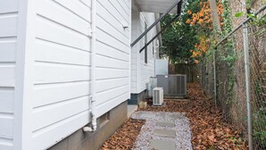 A narrow pathway leading to a white house with a covered porch and a chain-link fence. - Cozy studio in Columbia with WiFi, AC (Columbia)