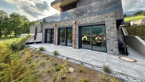 A modern house with a stone facade, large windows, and a sloped roof. - Apartment Alpinero 405 by we rent (Piesendorf)