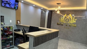 A hotel reception desk with a modern design, a mounted television, and a logo on the wall. - HOTEL MAGISTRAL SUITER (Quibdó)