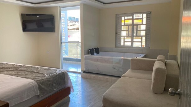 A bedroom with a bed, a sofa, a bathtub, and a TV. - HOTEL MAGISTRAL SUITER (Quibdó)