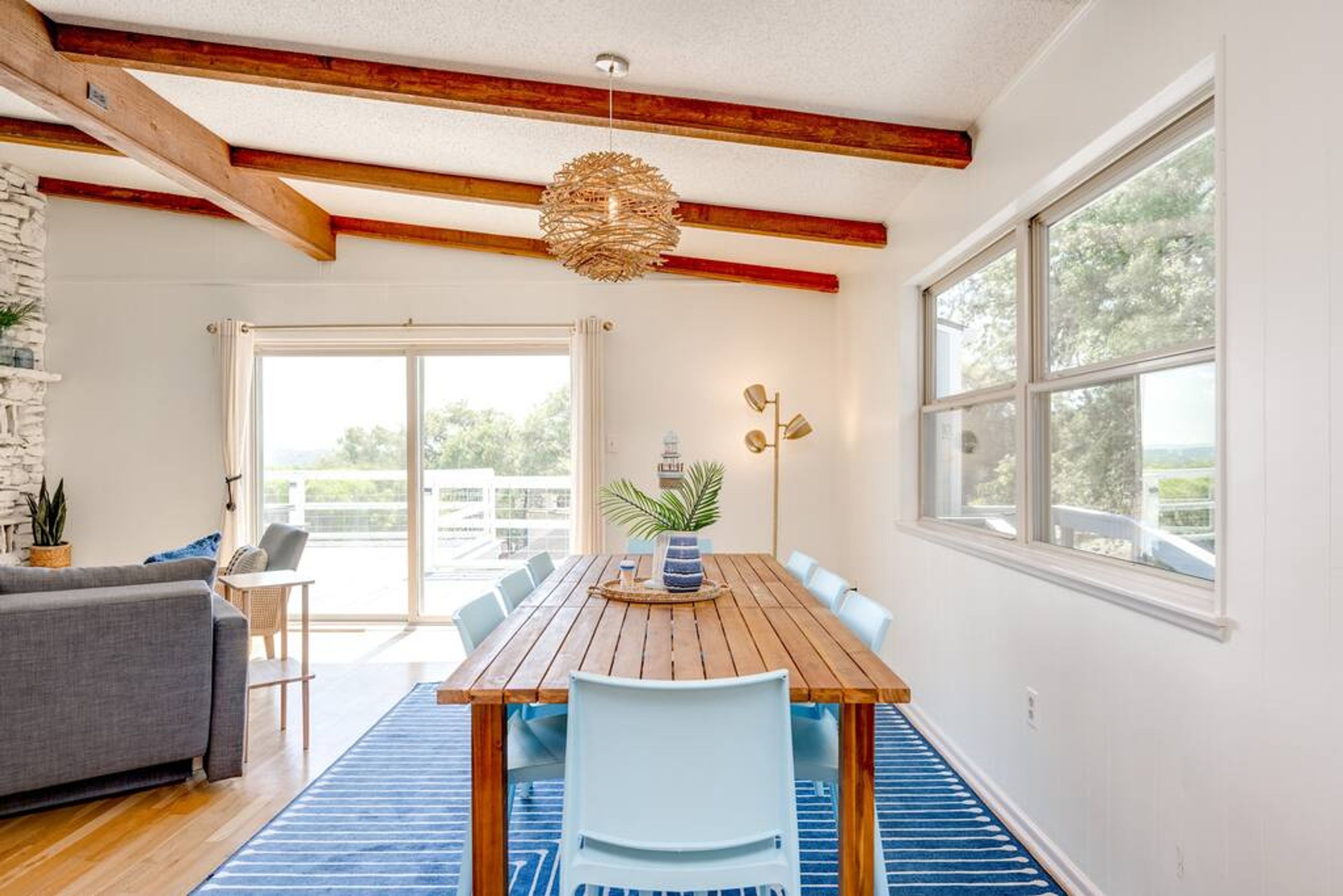 A dining area with a wooden table and chairs, a blue rug, and a stone wall.