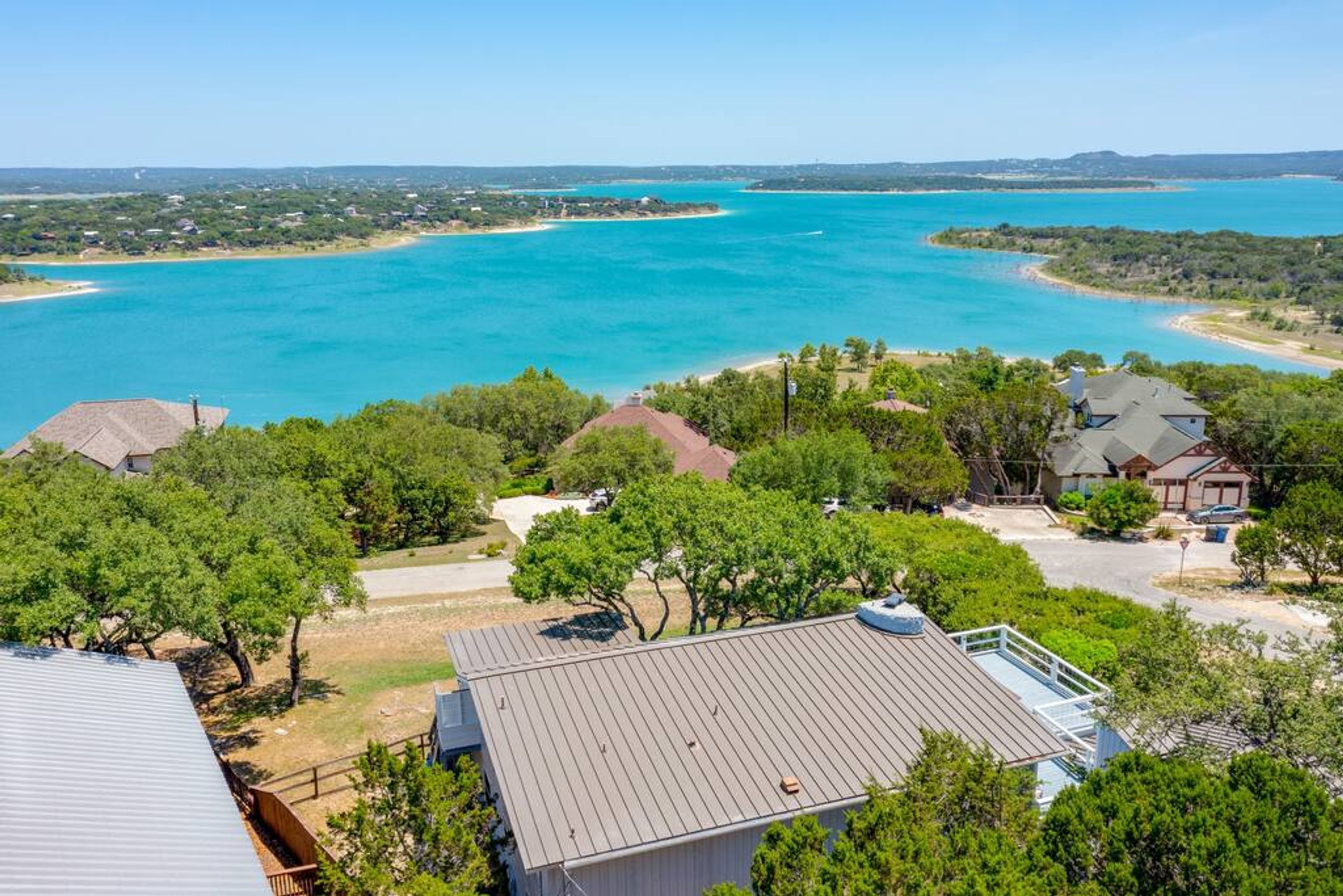 A coastal residential area with houses, a beach, and a large body of water.