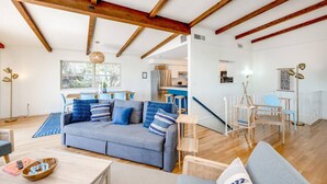 A spacious living area with a high ceiling and exposed wooden beams, a gray sofa with blue cushions, a dining table, and a view of the kitchen and dining area. - 4 2 wow 180 Lake Views hot tub Pickleball Tennis POA Court EV Charger Wheelchair Ramp POA Pool (Canyon Lake)