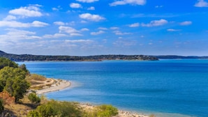 Un paisaje costero con cielo azul despejado, una playa arenosa y un mar tranquilo.