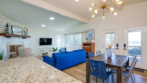 Una sala de estar moderna con un sofá azul, una mesa de comedor de madera y un televisor montado en la pared.