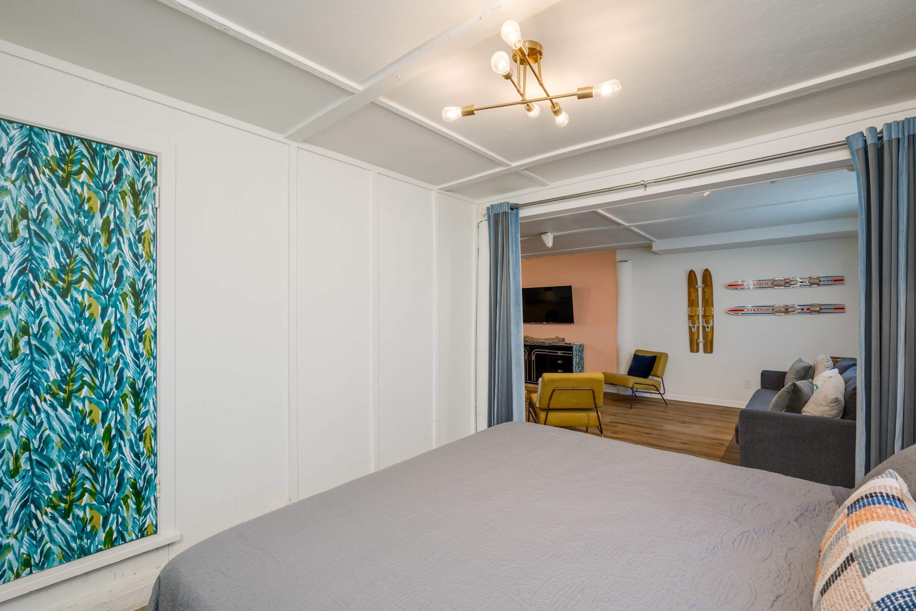 Een moderne hotelkamer met een groot bed, een televisie, een wand met ski-thema en een zithoek met een gele stoel.