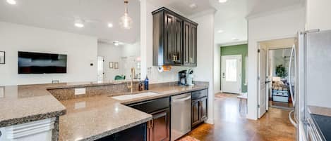 A modern kitchen with granite countertops, dark cabinetry, and stainless steel appliances.