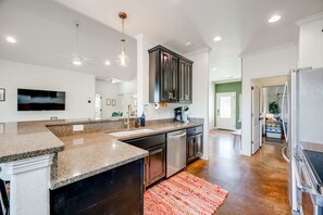Una cocina moderna con encimeras de granito, armarios oscuros y electrodomésticos de acero inoxidable.