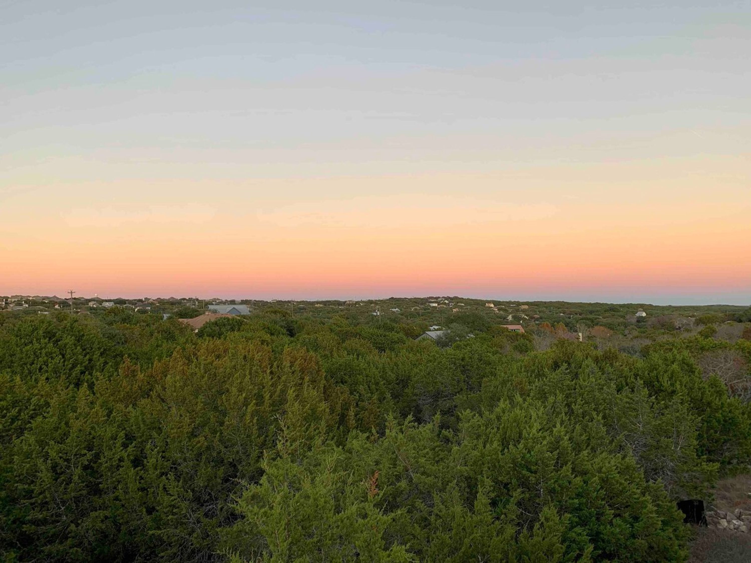 Paisagem com árvores verdes densas e uma vista distante de um pequeno povoado.
