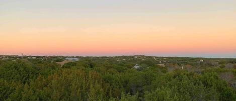Paisagem com árvores verdes densas e uma vista distante de um pequeno povoado.