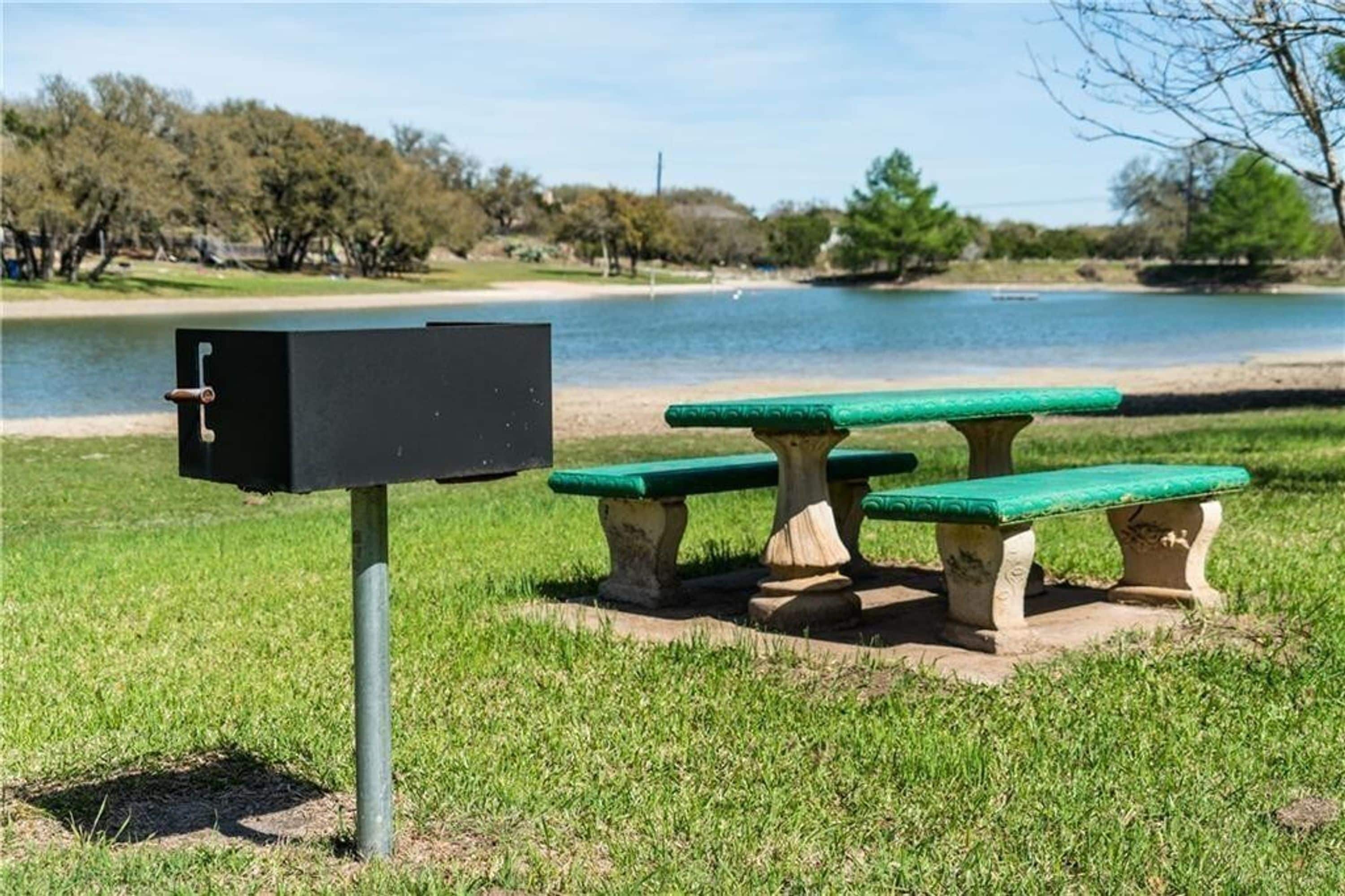 A mailbox, three green benches, and a lake in the background.