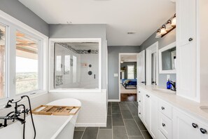 A modern bathroom with a bathtub, a shower, and a vanity with a mirror.
