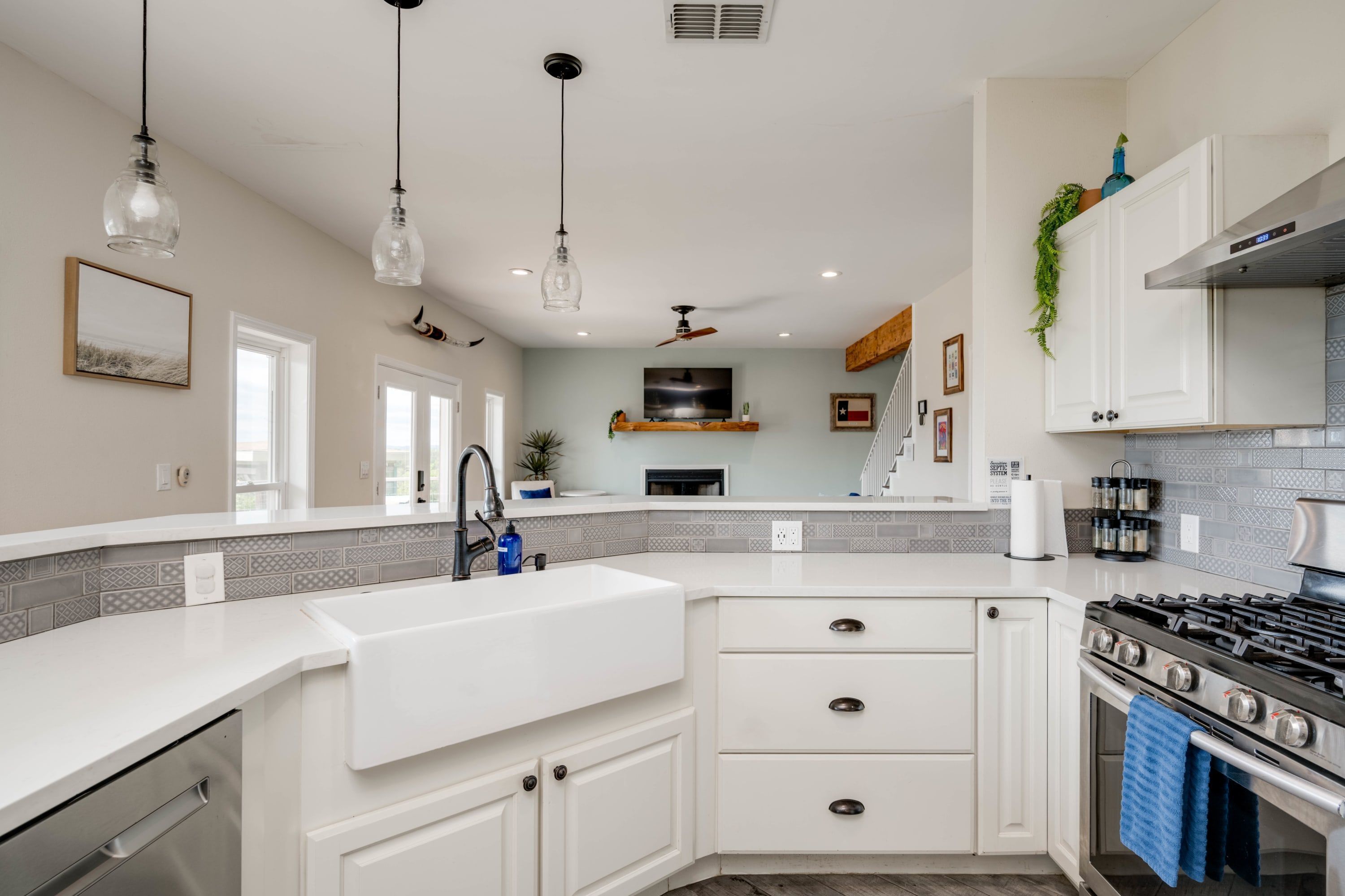 A modern kitchen with white cabinetry, a stainless steel stove, and pendant lighting.
