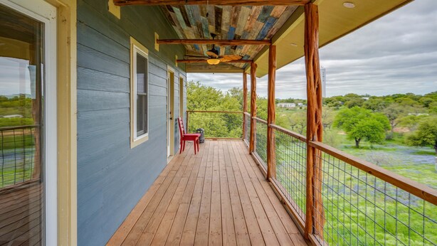 A covered porch with a wooden floor, a red chair, and a view of a green landscape. - 6bed 4bath 3 Acres With 18i0 Degree Views Pool Firepit (Buchanan Dam)