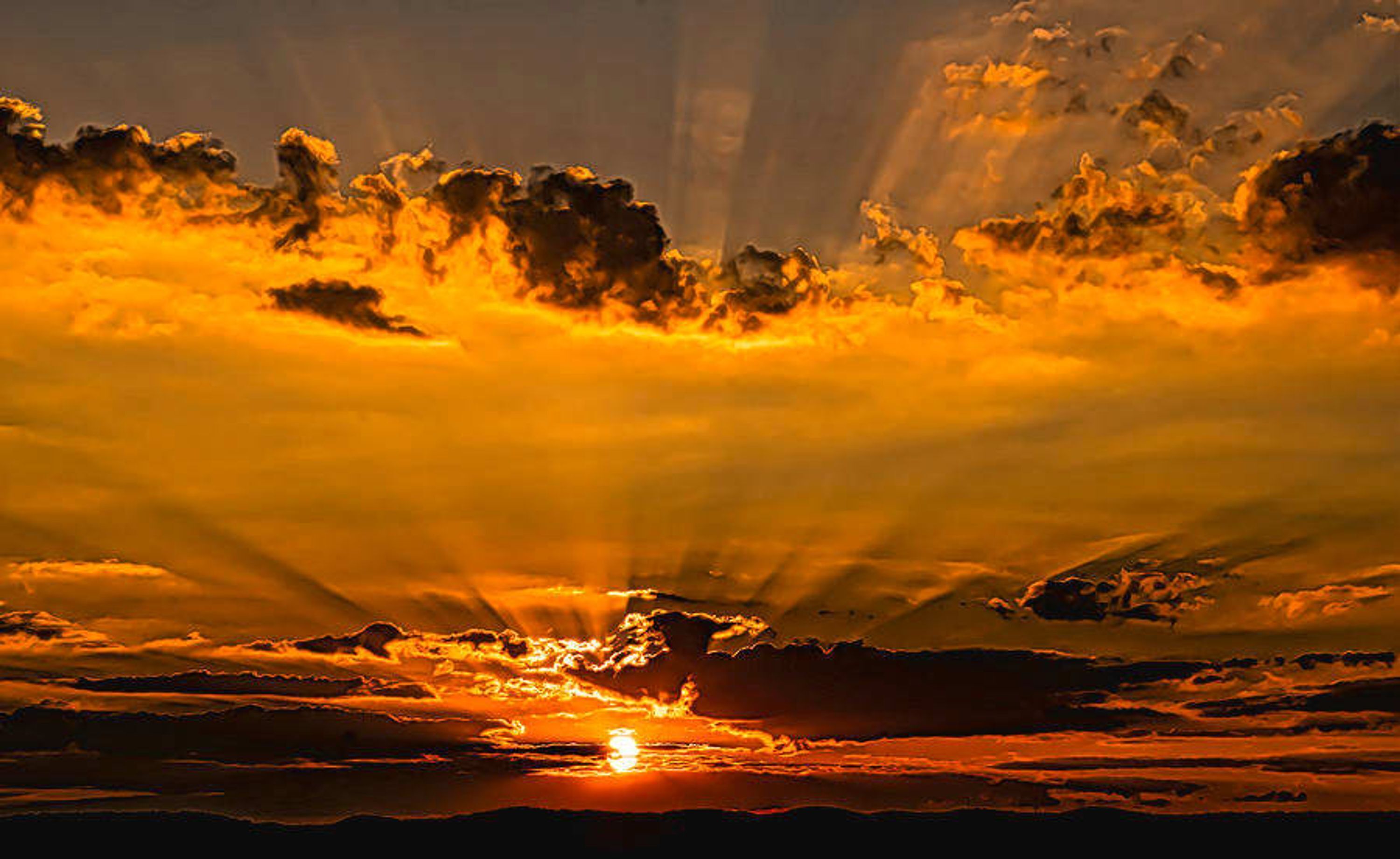 Un atardecer con rayos de sol atravesando las nubes.