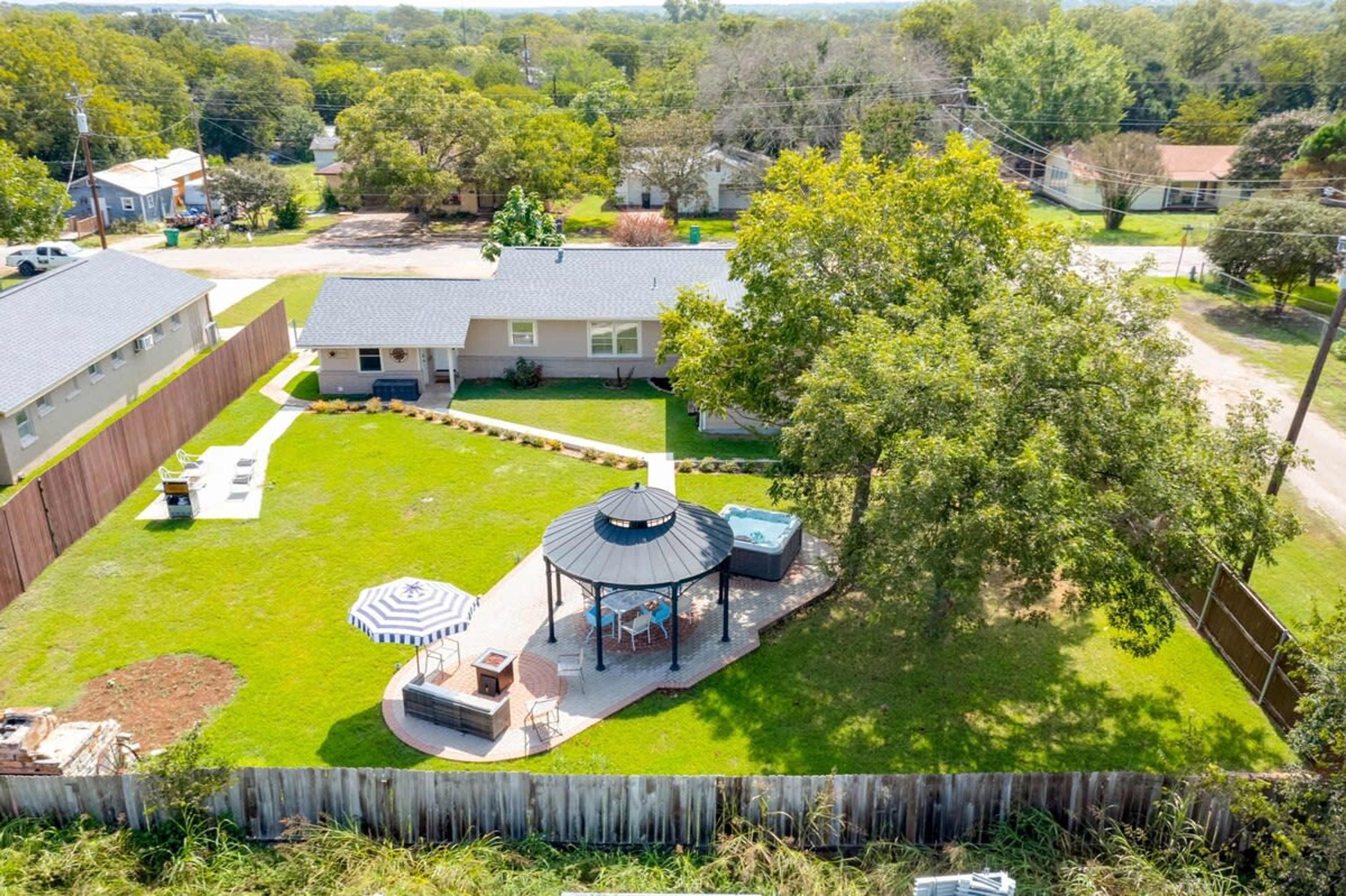 Un jardin à l’arrière d’une maison, aménagé avec un belvédère, une terrasse et une piscine.