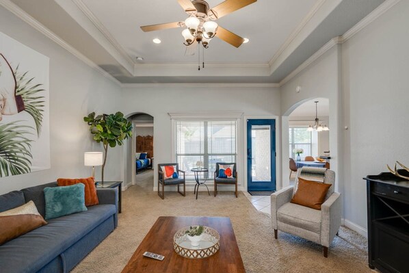 A living room with a ceiling fan, a coffee table, a sofa, and two armchairs.