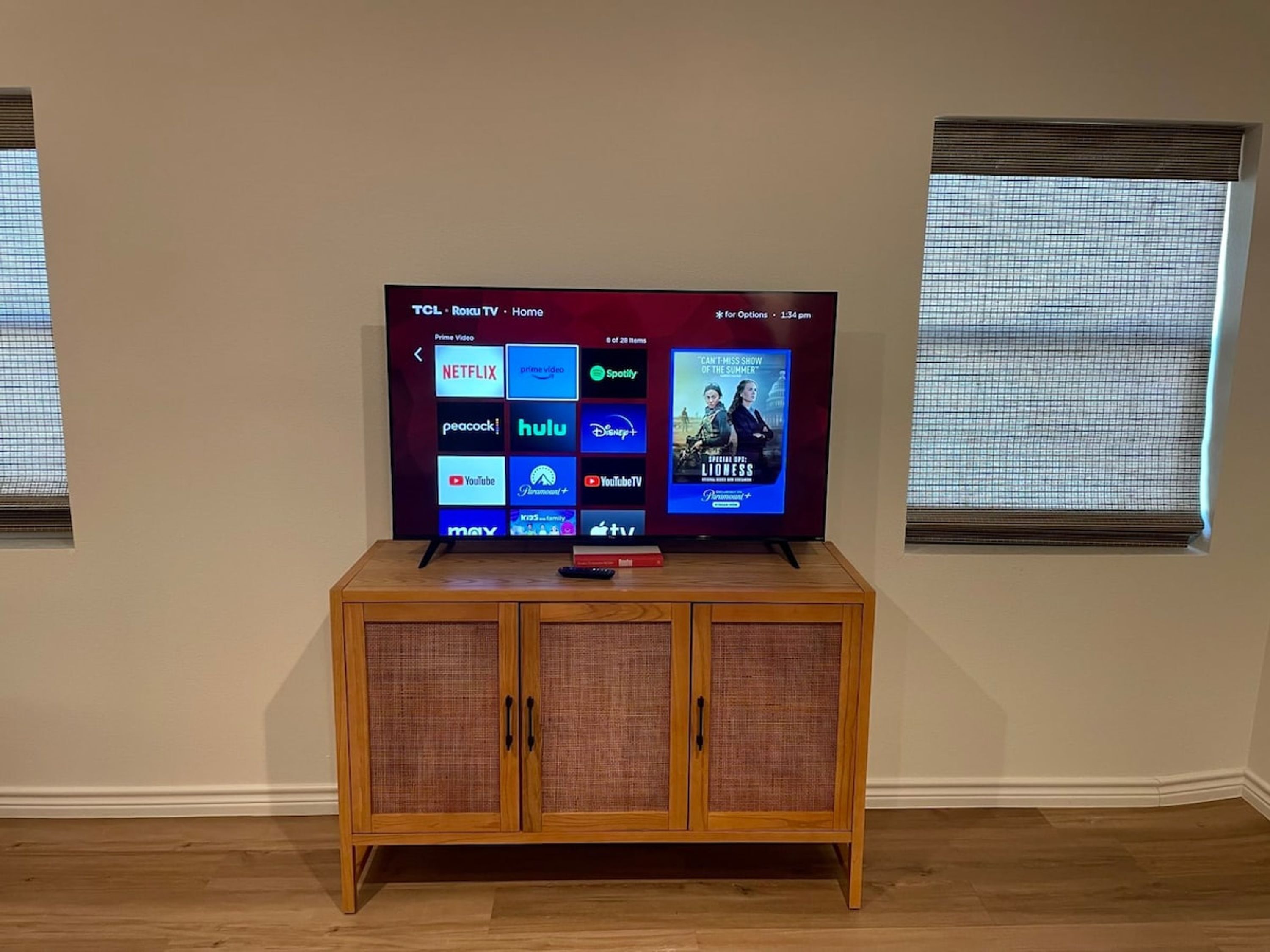 A flat-screen TV on a wooden cabinet with a screen displaying various streaming services.