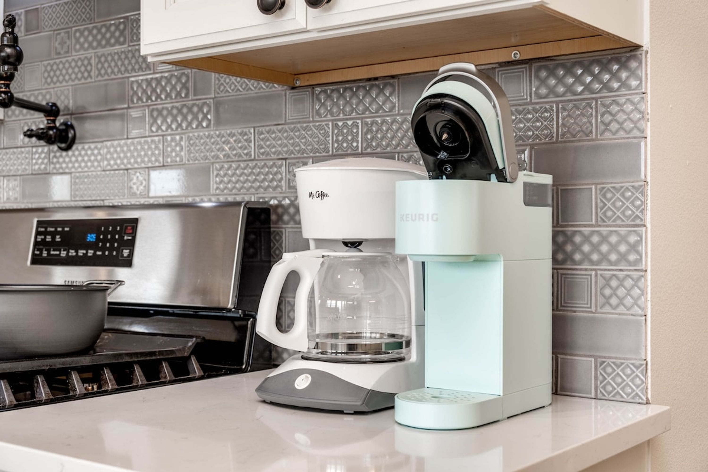 Uma cozinha moderna com cafeteira Keurig, fogão e panela.