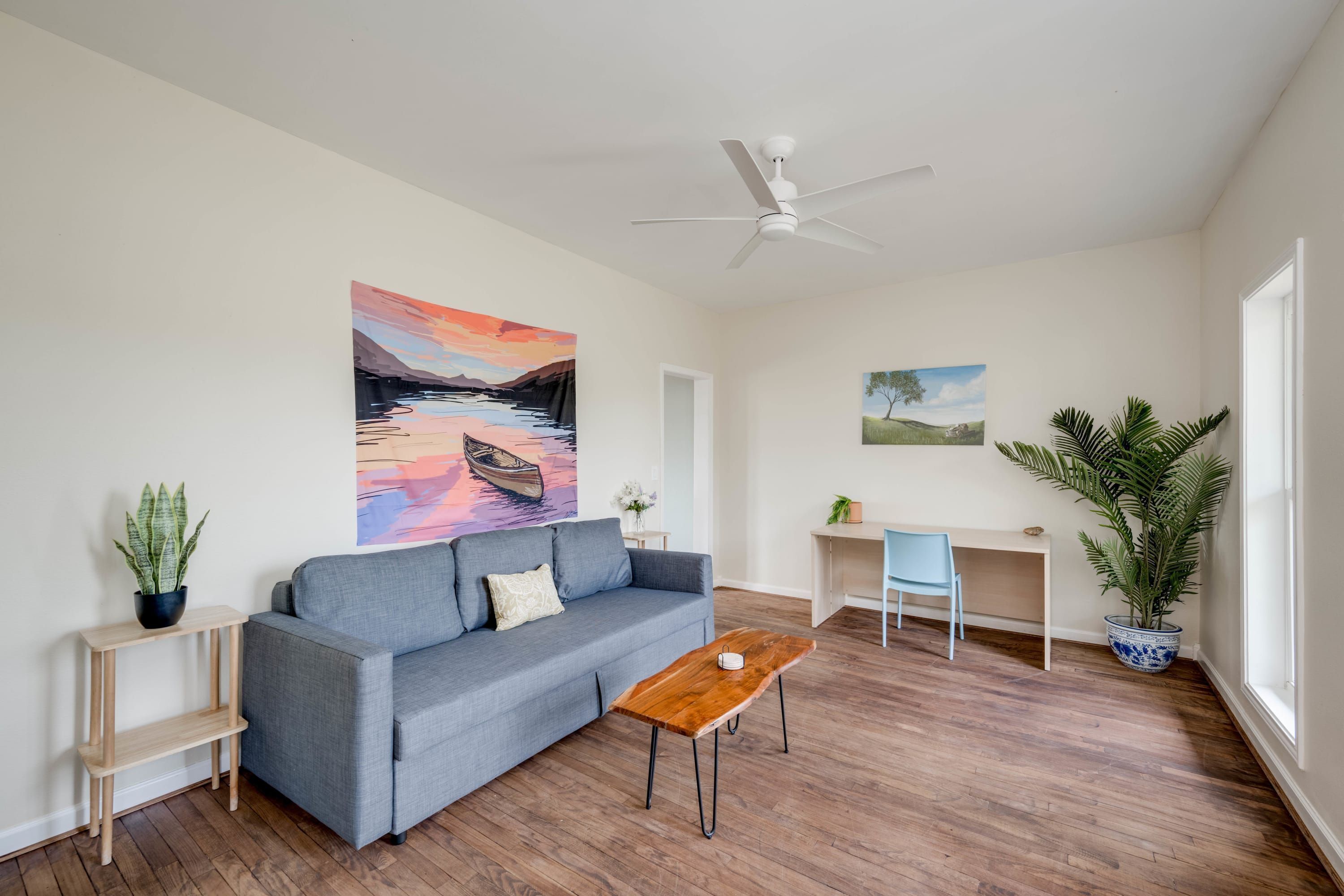 A modern living room with a grey sofa, wooden coffee table, and a ceiling fan.